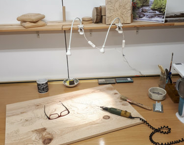 Vista del taller de Samu-Do en la que se ve una mesa sobre la hay una tabla de madera preparada para ser tallada y un cincel electrónico.