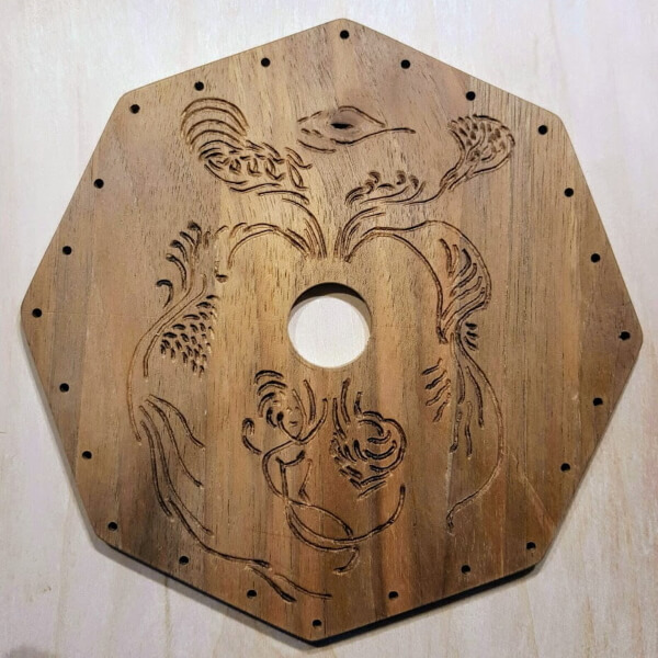 Base media octogonal del soporte para pendientes. Es de madera tallada con simbología y con agujeros en todo su perímetro para poder colocar los pendientes.